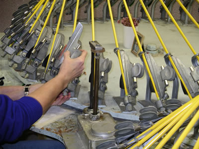 Applying glue to the base of the vane from a foot operated glue dispenser located to the right of the fletcher's hand before clamp is applied to the arrow shaft. The dispenser spindle then retracts into glue well and emerges with fresh glue when the foot pedal is depressed